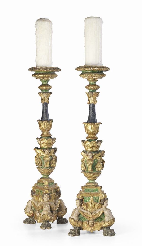 Due candelabri in legno intagliato, dorato e laccato verde e nero