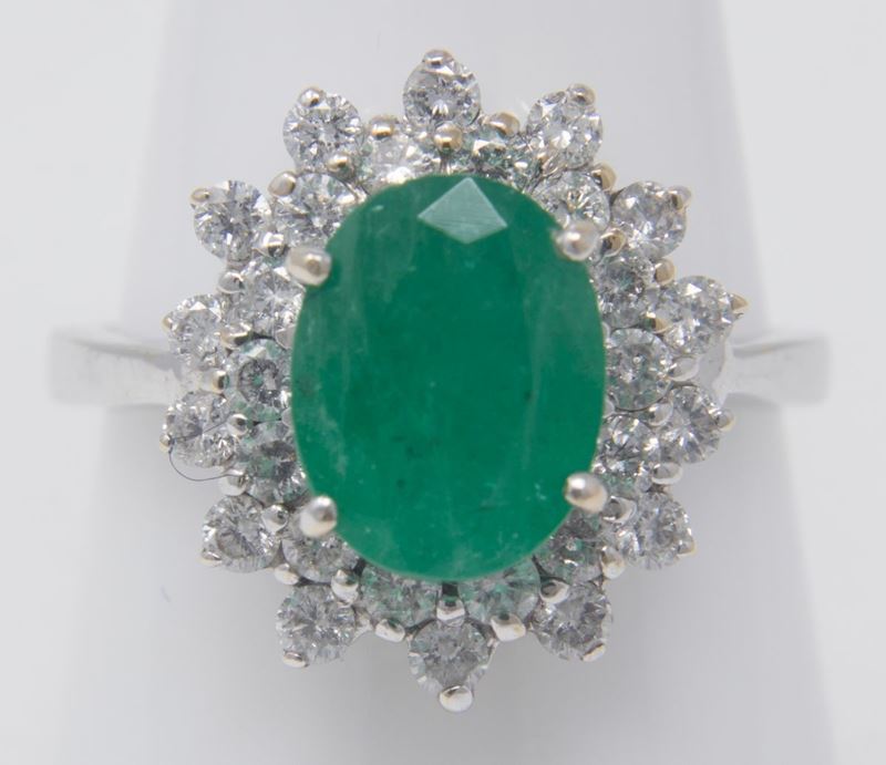 Anello in Oro Bianco a Margherita con Smeraldo Ovale Centrale e Due File di Brillanti Laterali