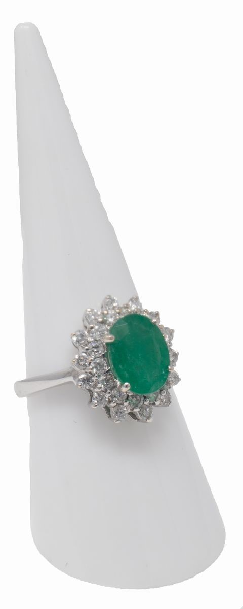 Anello in Oro Bianco a Margherita con Smeraldo Ovale Centrale e Due File di Brillanti Laterali